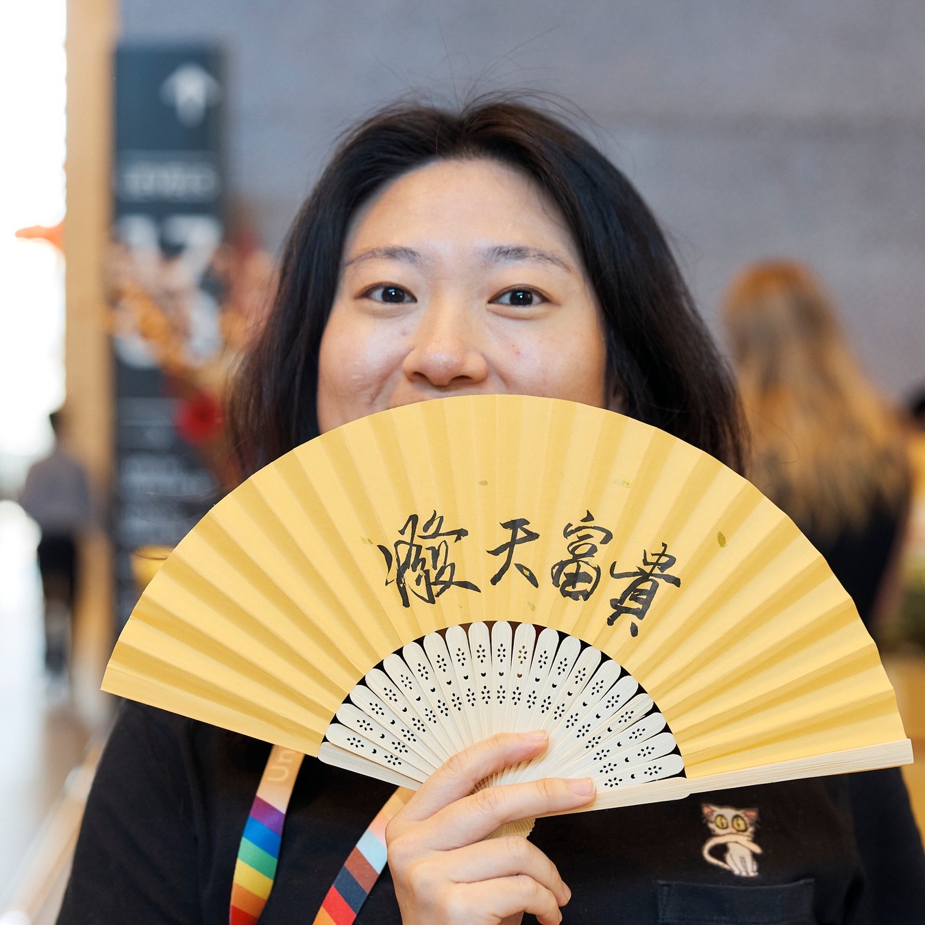 A guest proudly displaying a yellow handheld fan personalised with Chinese calligraphy, created during a live cultural calligraphy event.
