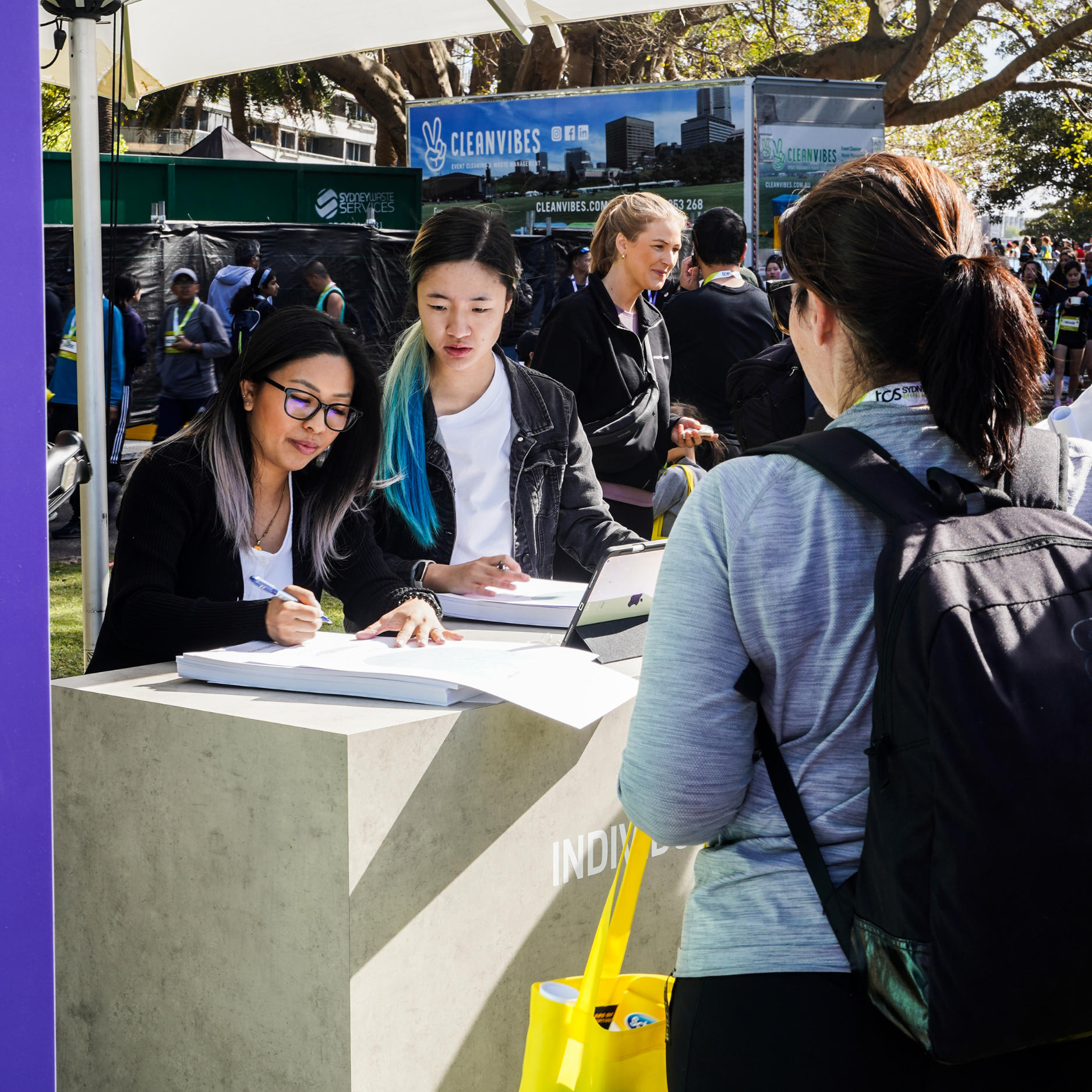 Kimlligraphy team members engaging with attendees at an outdoor individualisation station, providing personalised services during a lively public event