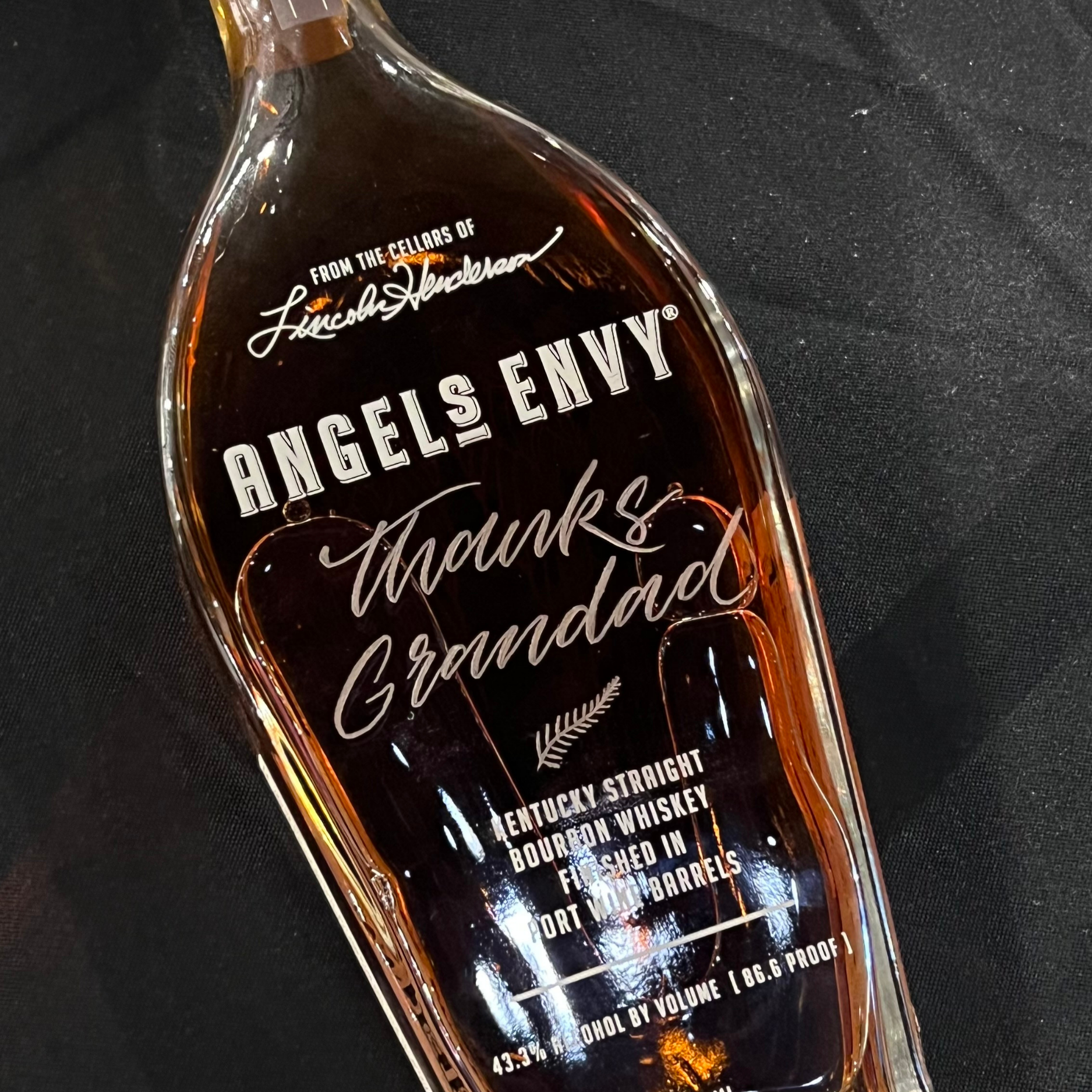 A personalised Angel's Envy whiskey bottle with engraved calligraphy, reading "Thanks, Grandad" under the brand's label, creating a unique and heartfelt gift.