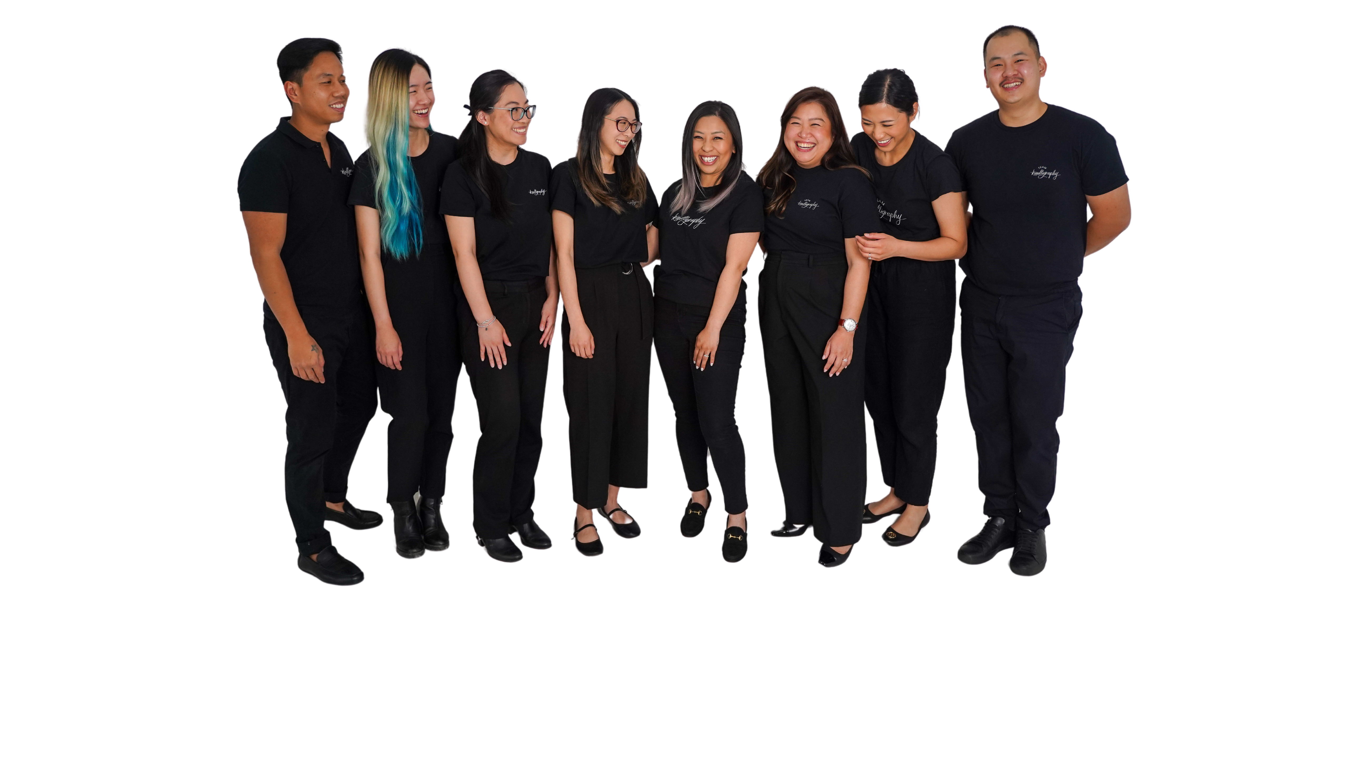 A group photo of the Kimlligraphy team, all dressed in matching black 'Kimlligraphy' branded t-shirts, smiling and laughing together. The team stands in a line, showcasing a cohesive and friendly professional environment.